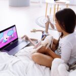 photograph of a girl watching on a laptop with her stuffed toys