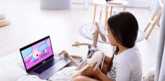 photograph of a girl watching on a laptop with her stuffed toys